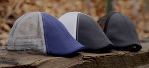 Trucker Scally Caps are here, photo shows 3 hats in Black/Black, Black/White and Navy/Grey sitting on a wooden table