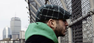 A man wearing a Scally Cap looking over a fence