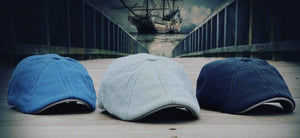 The Captain, image showing three 8-panel caps in varying colors (blue, green, black) sitting on a dock with a pirate ship behind