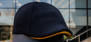The Cheevers cap is here, showing a black cap with a yellow brim in front of the Bruins hockey rink