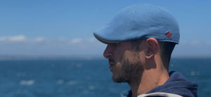 Man wearing the Tide Blue Sailor Scally Cap in front of a body of water